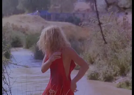 Голая блондинка стирает платье в реке