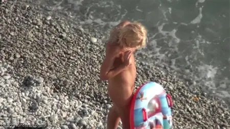 Молодая блондинка плавает в море голышом на надувном матрасе